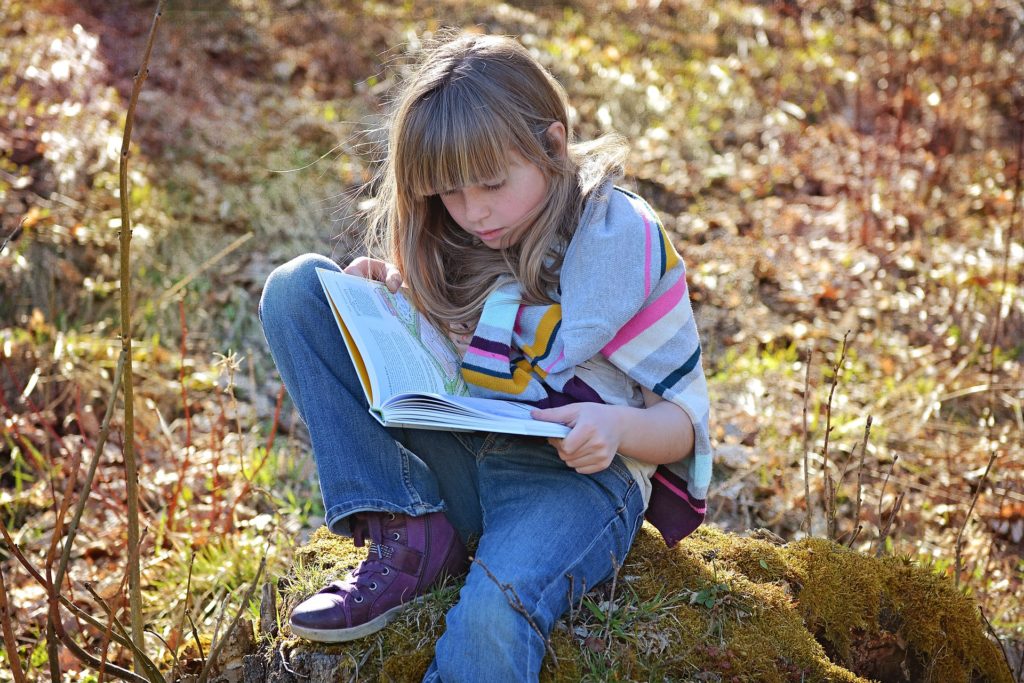 girl (about 10 years old) read the book in the forest.